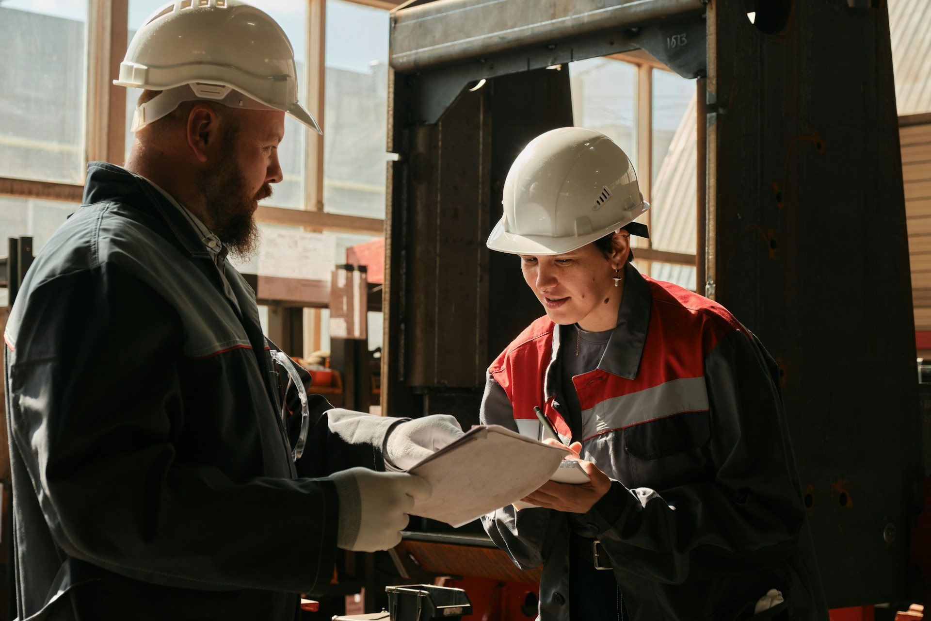 Dos personas con casco revisando documentación técnica en una planta industrial